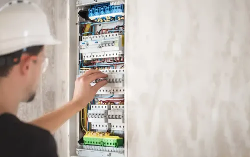 électricien qui répare un tableau électrique